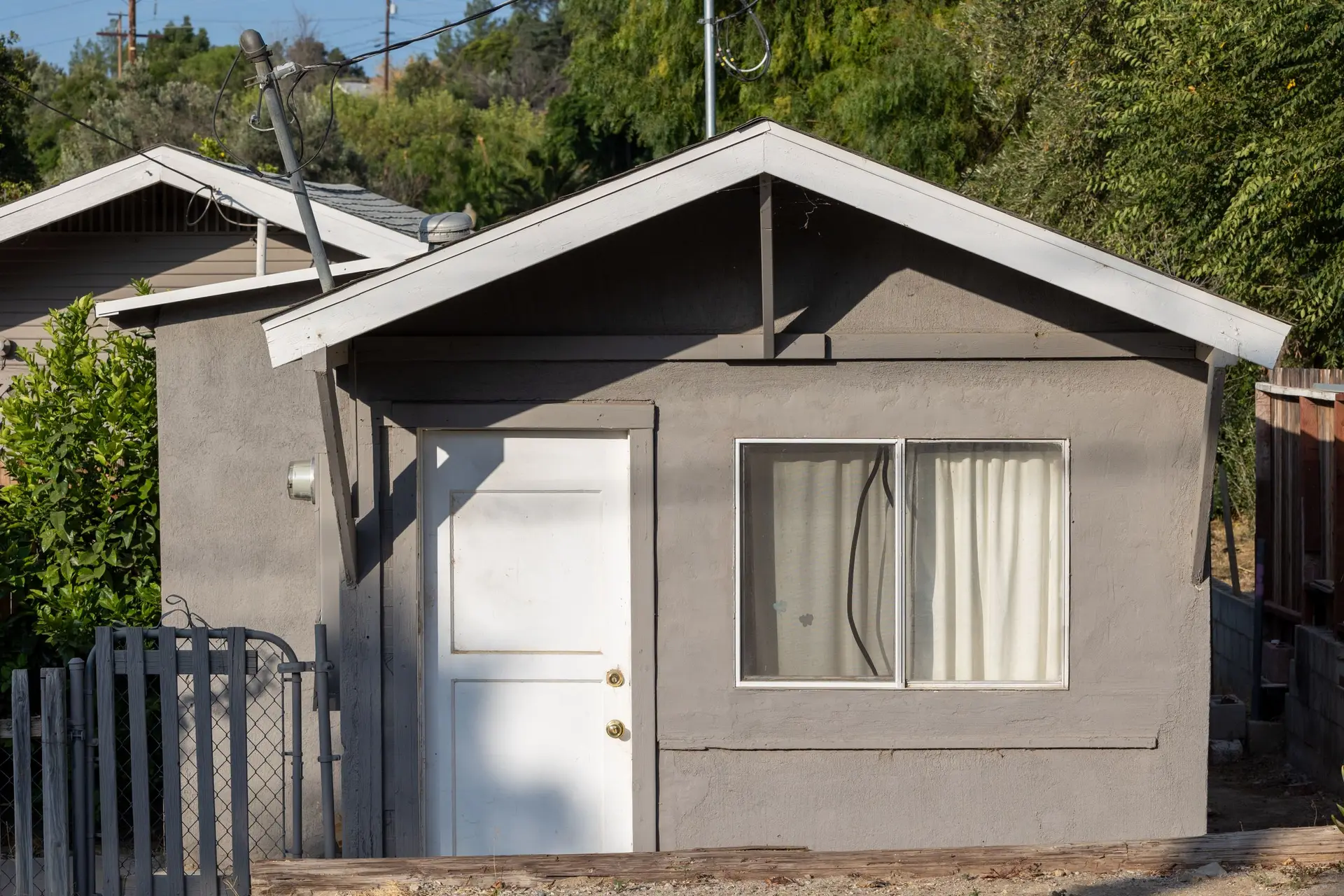 Small gray backyard cottage with a white door and a side window