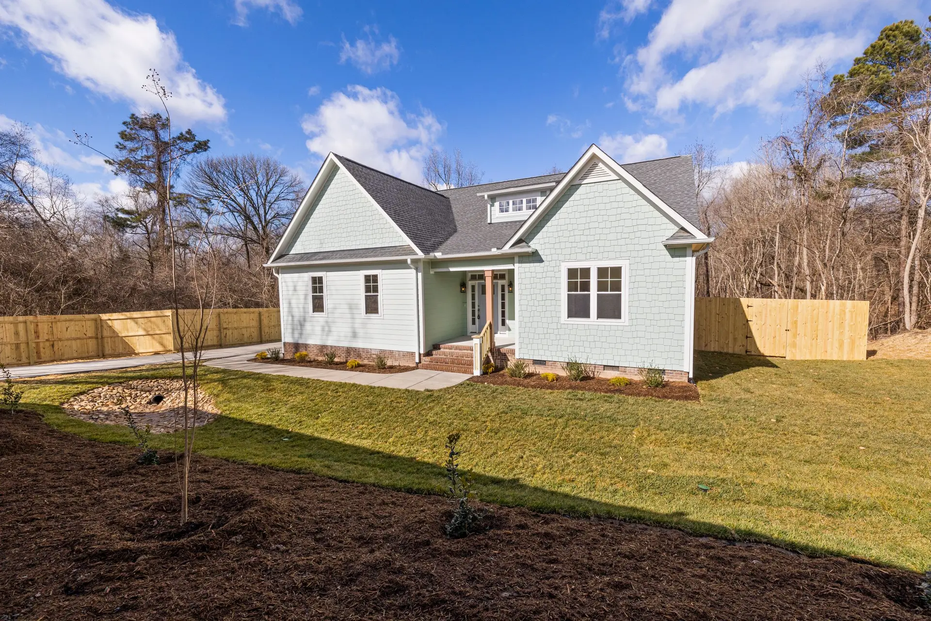 Newly built gray house with a porch on a freshly graded lot