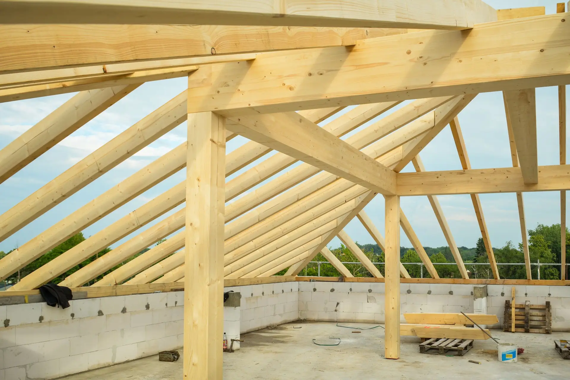 Pale timber roof trusses over the walls of an unfinished building