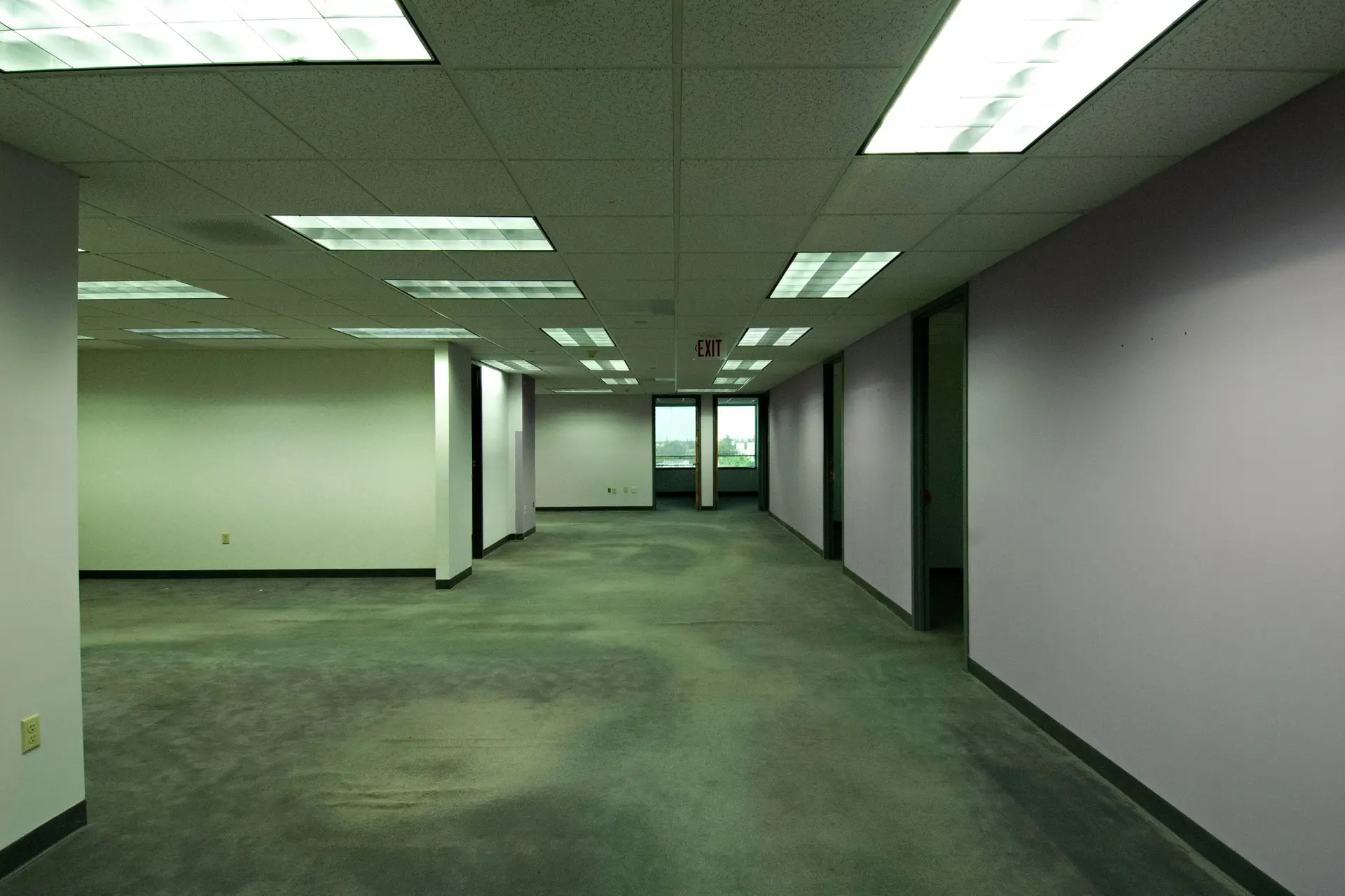 Empty office floor with fluorescent ceiling lights and gray carpet
