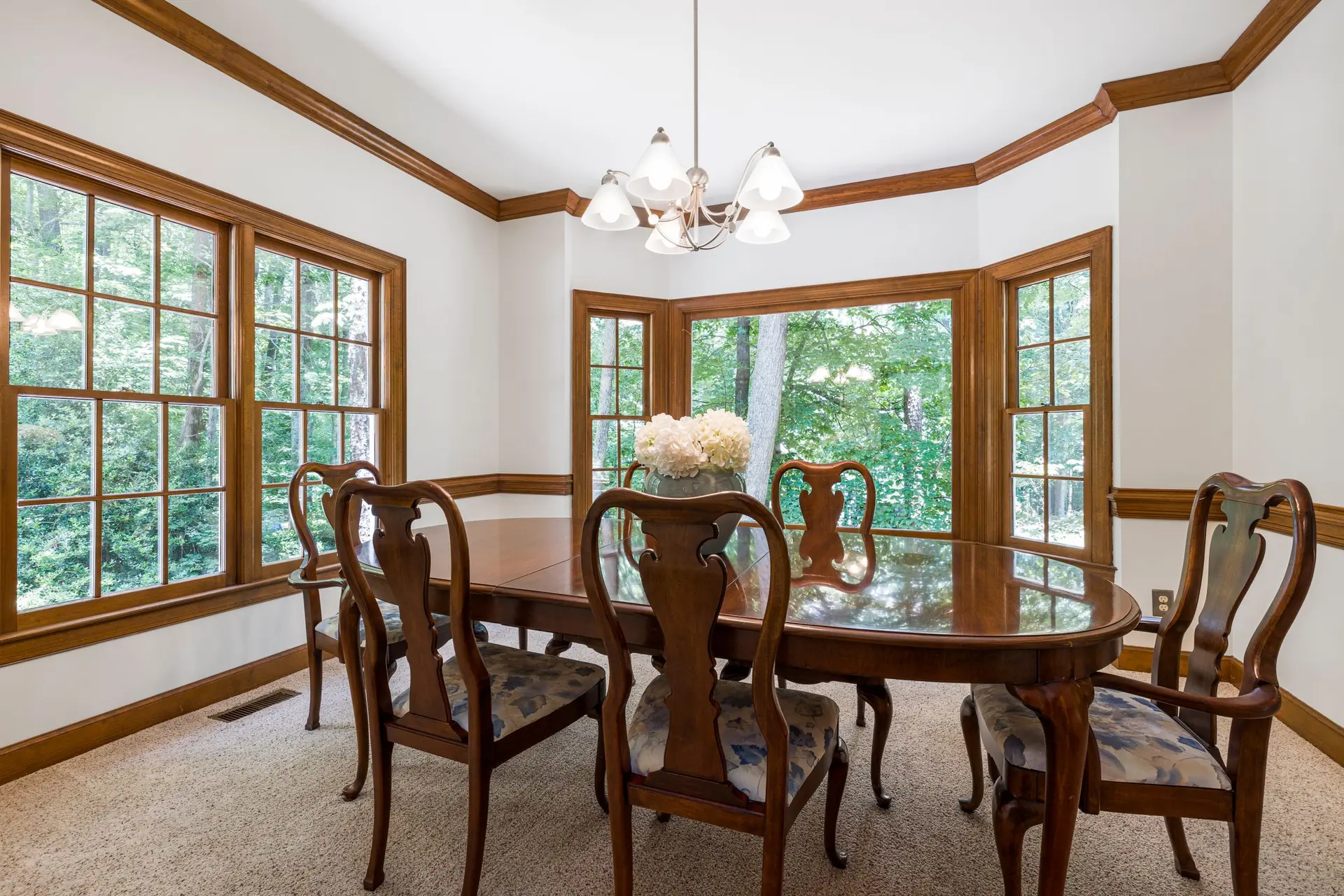 Dining room with stained wood window trim and a bay of tall windows